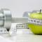 apple, measuring tape and chrome dumbbell