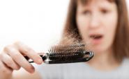 horrified woman holding a brush full of hair