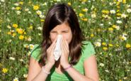 child with hayfever blowing her nose in a meadow