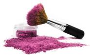Rose-colored mineral makeup spilling out of the jar with kabuki brush