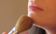 woman applying bronzer to chin